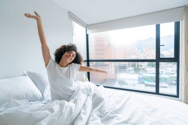 Beautiful african american woman waking up in the morning and yawning in bed